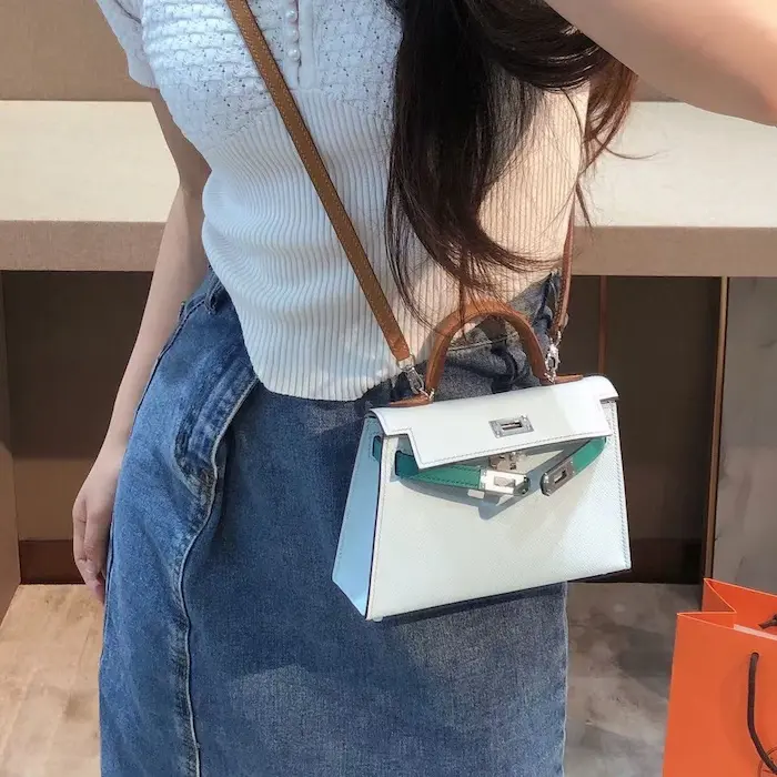 Woman carrying Bleu Saphir replica Hermes Kelly 19cm with jeans and white shirt