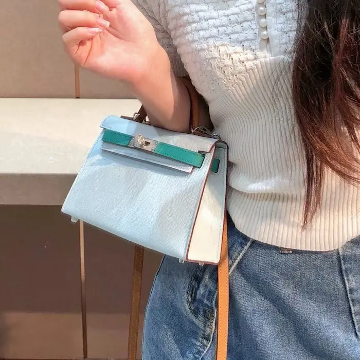 Overhead shot of replica Hermes Kelly 19cm in Bleu Saphir Epsom leather being carried