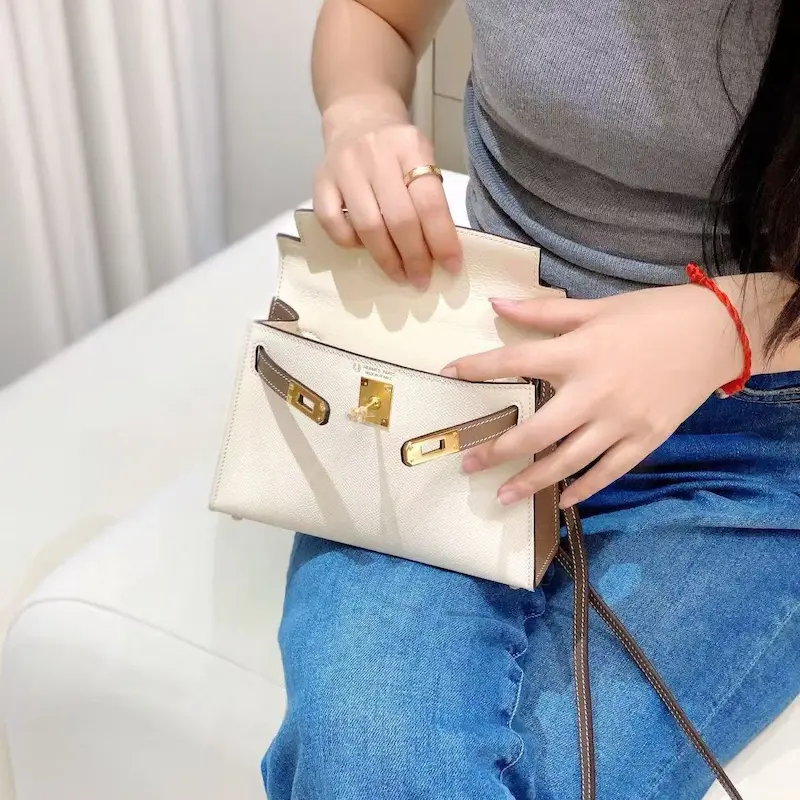 Close-up of model opening white replica Kelly 19cm bag showing interior organization