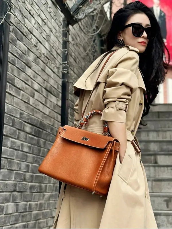 Close-up of replica Hermes Kelly 32cm Gold top handle carry with blazer outfit