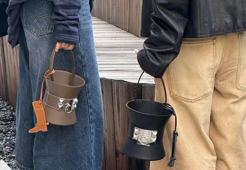 Stylist carrying replica Hermès Mini Medor bags in black and étoupe grey