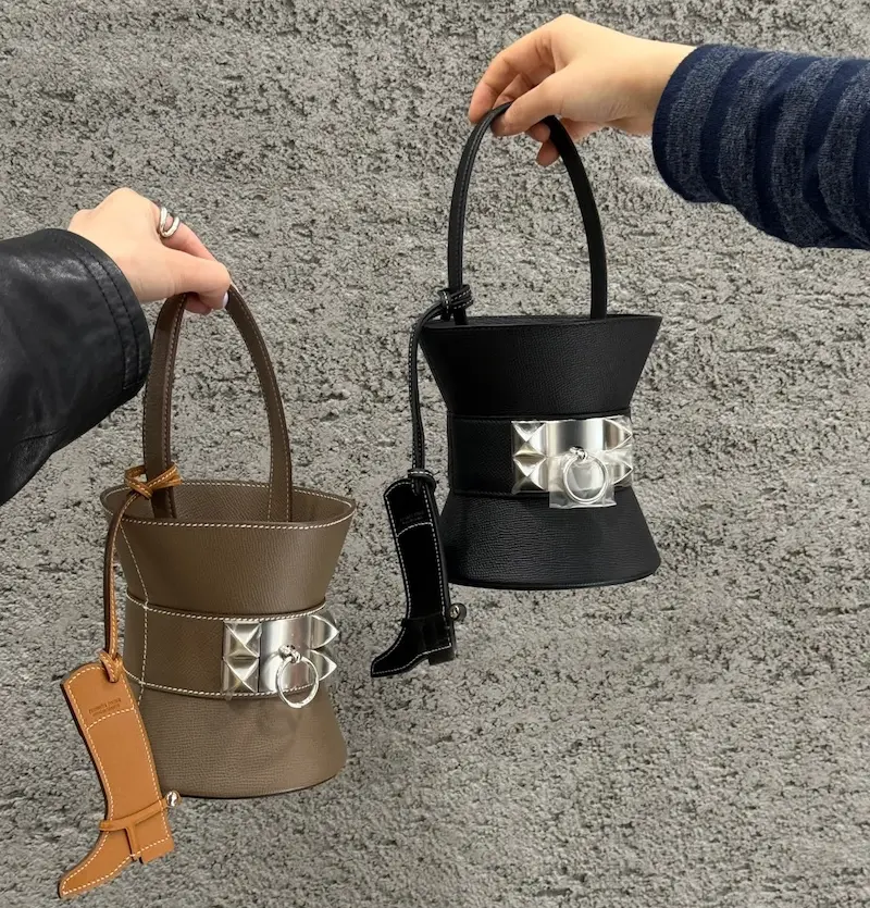 Stylist hand carrying black Epsom leather Mini Medor replica bag by its chain strap