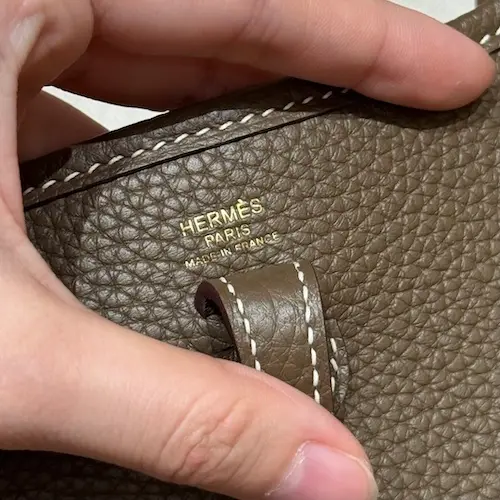 Closeup of perforated H logo on Hermes Evelyne TPM replica flap interior