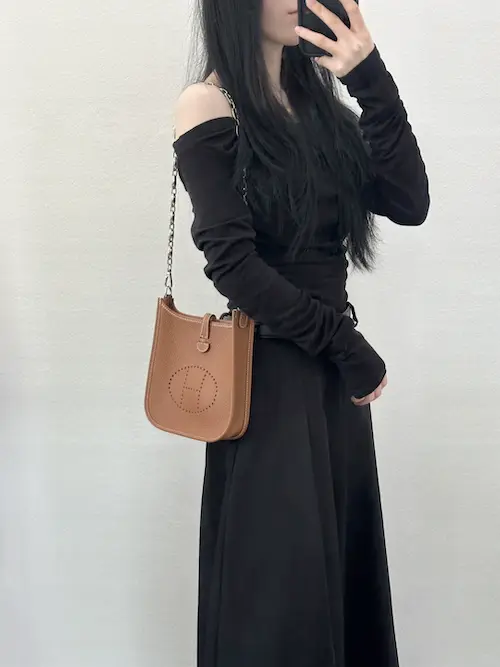 Woman wearing gold Hermes Evelyne TPM replica crossbody bag with casual outfit