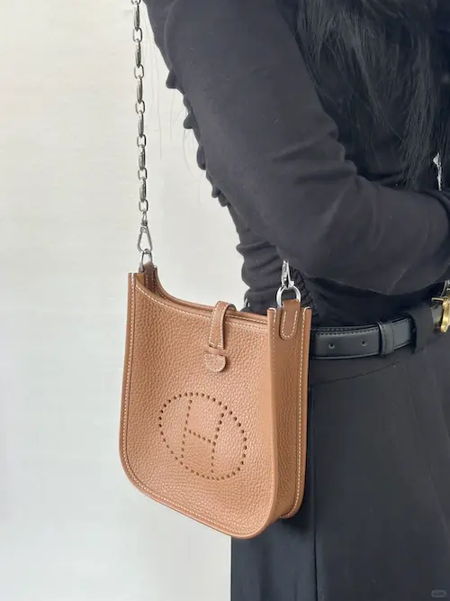 Side view of gold Evelyne TPM replica bag worn crossbody with jeans