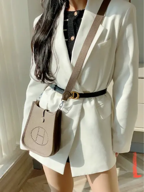 Angled view of elephant grey Evelyne replica bag on shoulder