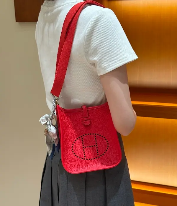 Model wearing bright red Evelyne 16 replica bag crossbody with dress