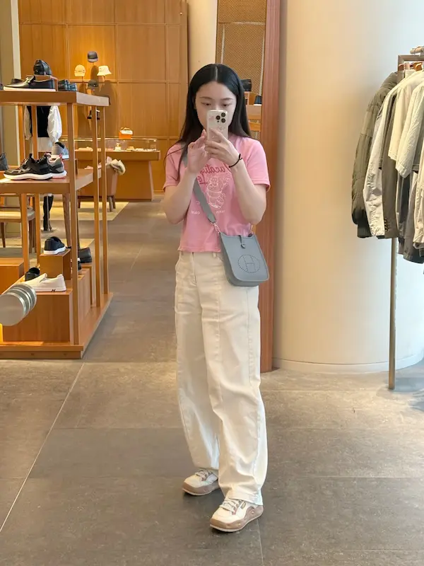 Woman wearing blue Hermes Evelyne TPM replica crossbody bag outfit styling