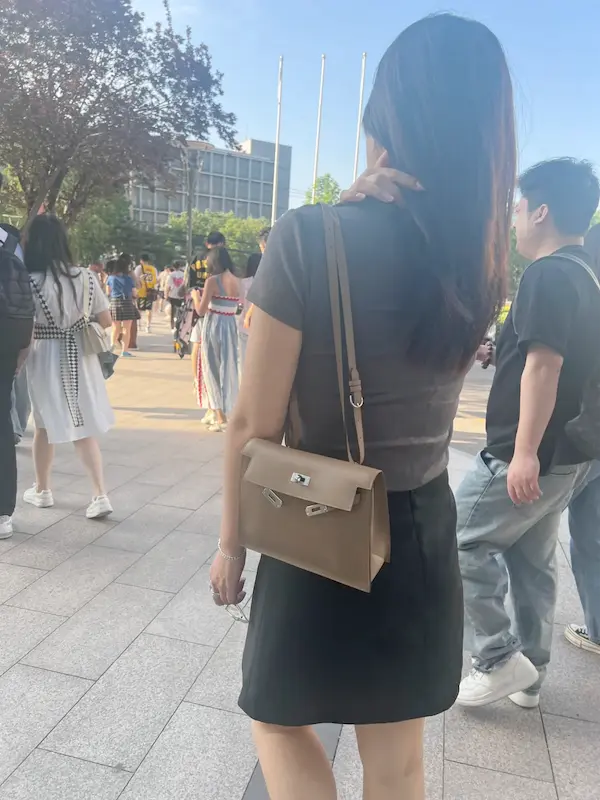 Styling Etoupe Grey Hermes Kelly Danse Replica for Urban Commute Woman wearing Etoupe Grey Replica Hermes Kelly Danse crossbody with coffee in city setting