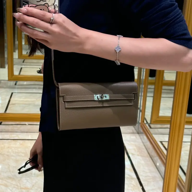 Woman carrying replica Hermes Kelly To Go Wallet in Elephant Grey crossbody style