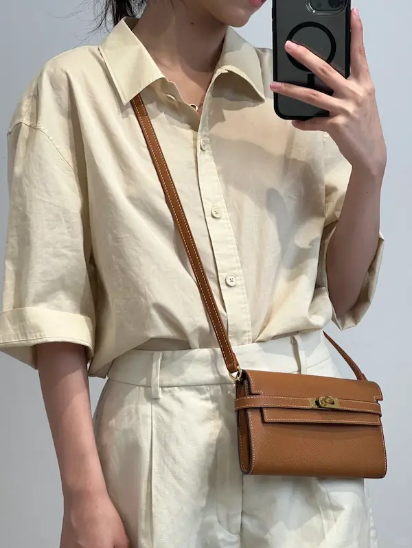 Side view of gold replica Kelly To Go wallet worn crossbody showing hardware details