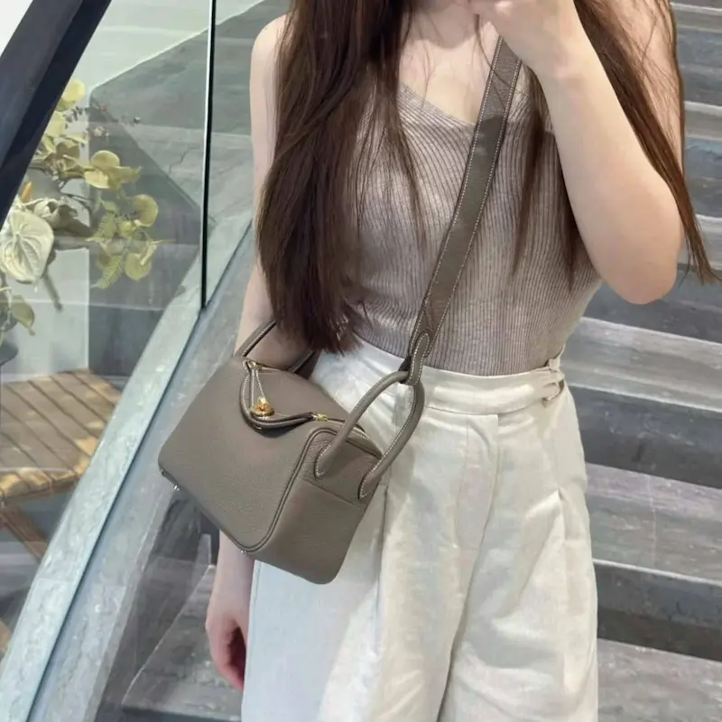 Woman wearing replica Hermes Lindy 19 in Etoupe gray crossbody style